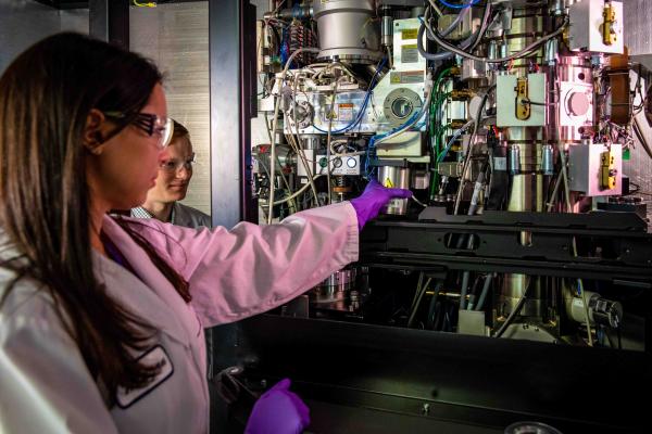 Research associate Megan Mayer and graduate student Patrick Mitchell load a sample into a cryogenic electron microscope at SLAC.