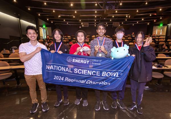 High school students hold up a blue National Science Bowl banner.